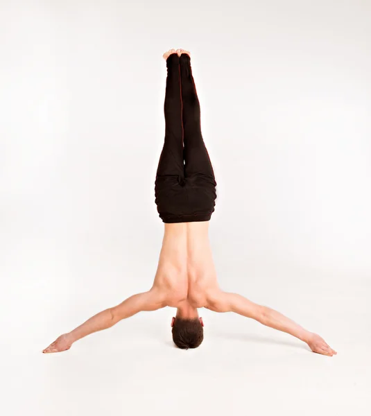 Slender man doing gymnastic exercises. Gymnast standing on hands — Stock Photo, Image