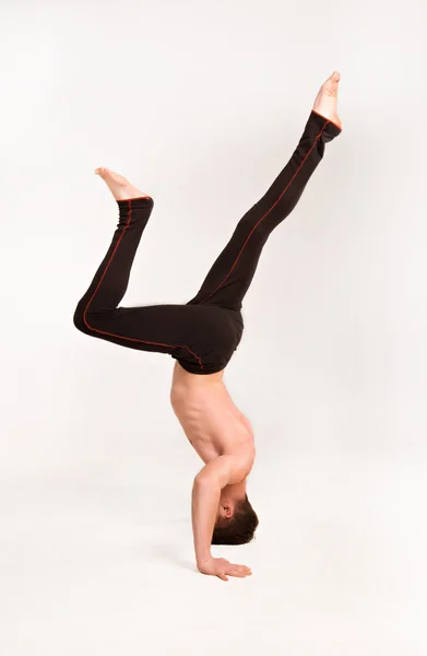 Slender man doing gymnastic exercises. Gymnast standing on hands — Stock Photo, Image