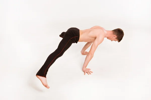 Slender man doing gymnastic exercises. Gymnast standing on hands — Stock Photo, Image