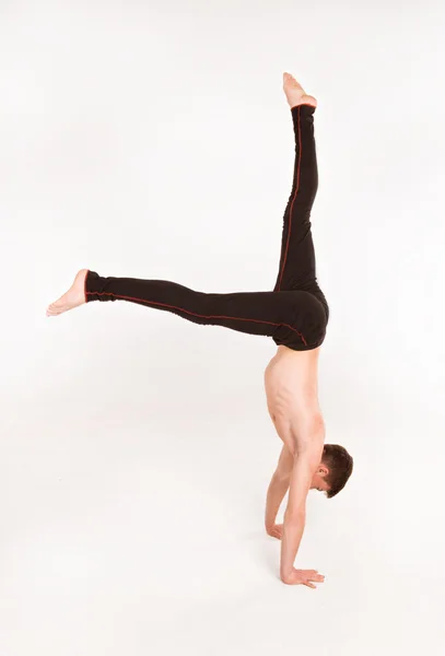 Homem esbelto fazendo exercícios de ginástica. Ginasta de pé sobre as mãos — Fotografia de Stock