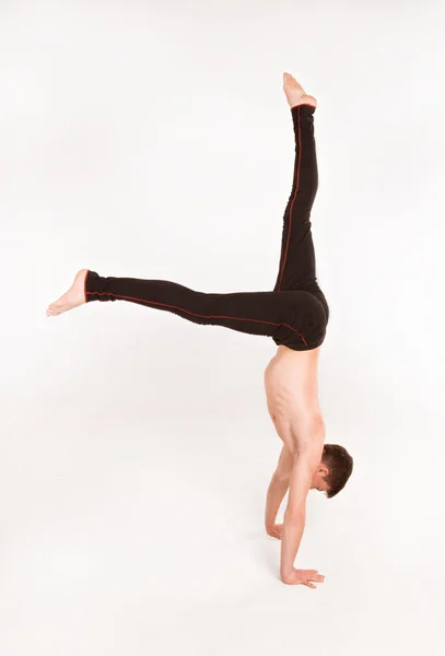 Slender man doing gymnastic exercises. Gymnast standing on hands — Stock Photo, Image