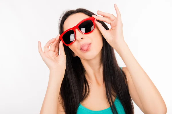 Divertido joven asiático mujer con gafas rojas mostrando lengua — Foto de Stock