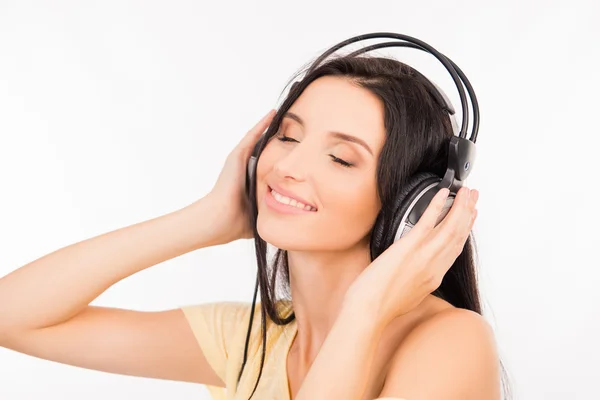 Söt ung kvinna njuter av musik i hörlurar, leende och nära — Stockfoto