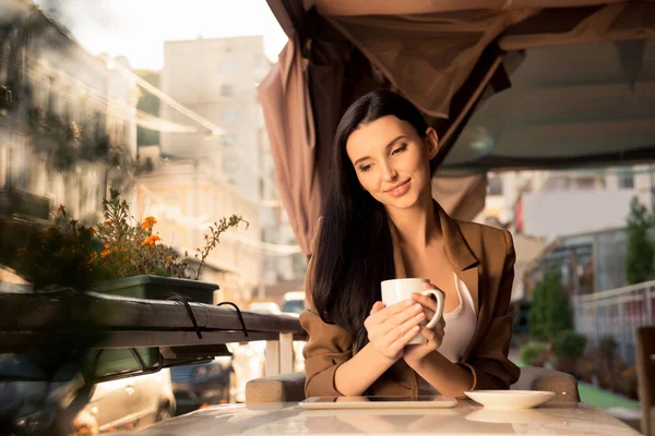 Bella ragazza seduta in un caffè sulla terrazza con una tazza di caffè — Foto Stock