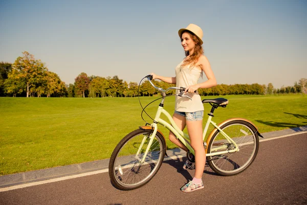 Счастливая симпатичная девушка с велосипедом, гуляющая по парку — стоковое фото
