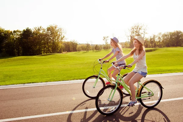 Positivo feliz niñas en el amor andar en bicicleta en el parque — Foto de Stock