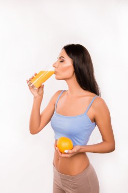 sexy athletic young woman drinking orange juice and holding oran clipart