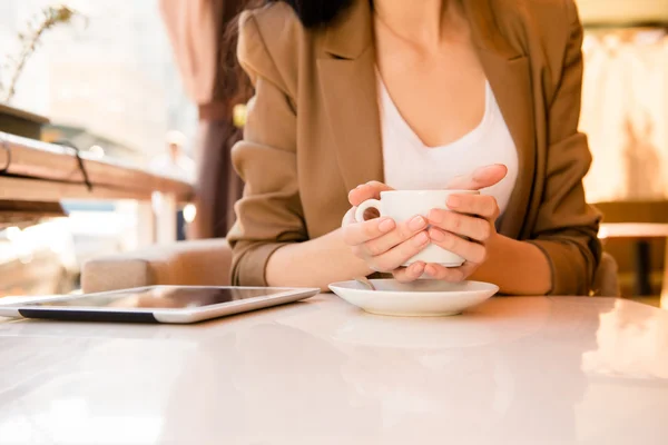 Young woman holding cup of coffee in cafe with tablet — Stock Photo, Image