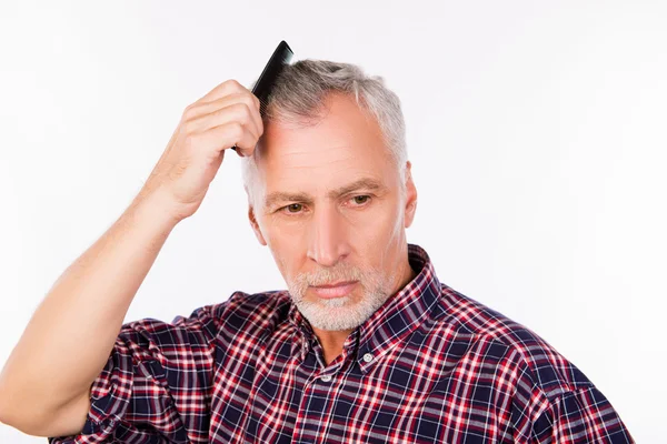 Сірий літній чоловік розчісує волосся — стокове фото