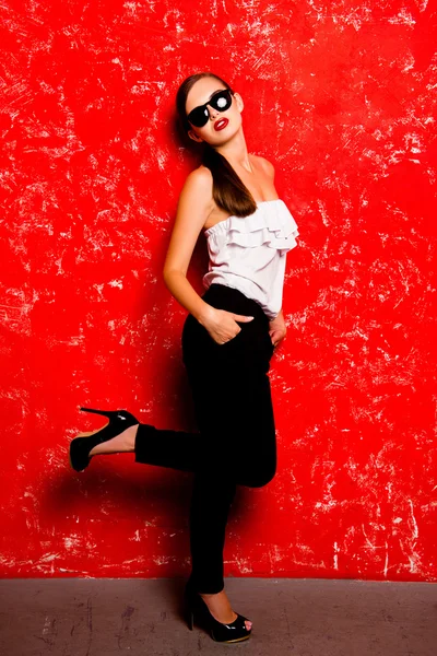 Menina glamourosa com lábios vermelhos e óculos posando contra o r — Fotografia de Stock