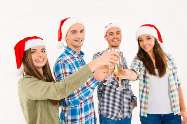 Šťastní lidé v santa klobouky slavit Vánoce s champagne — Stock fotografie