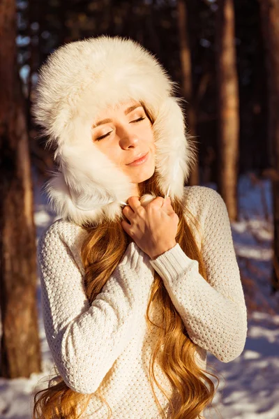 Menina bonito feliz vestindo chapéu de pele branca no inverno floresta fechando — Fotografia de Stock