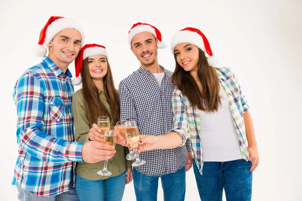 Mladí lidé v santa klobouky slavit Vánoce s champagne — Stock fotografie