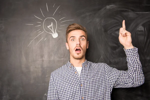 Jonge man tegen de achtergrond van een idee schoolbord — Stockfoto