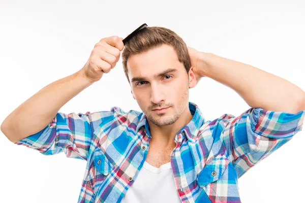 Bonito jovem confiante penteando seu cabelo — Fotografia de Stock