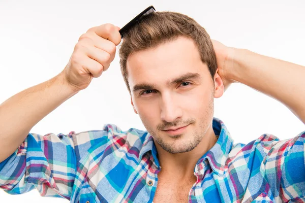 Красивий нахабний молодий чоловік розчісує волосся — стокове фото
