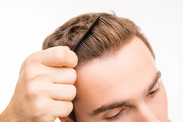 Primeros planos de un joven guapo peinándose el pelo — Foto de Stock