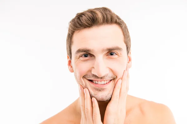 Komea mies koskettaa kasvojaan parranajon jälkeen — kuvapankkivalokuva