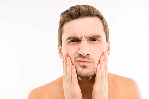 Handsome disturbed young man touching his face after shave — Stock Photo, Image