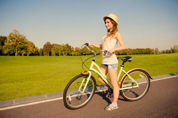 Счастливая симпатичная девушка с велосипедом, гуляющая по парку — стоковое фото