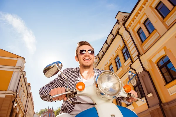 Schöner, fröhlicher Mann mit Sonnenbrille auf einem Motorroller — Stockfoto