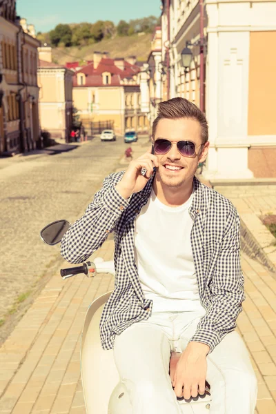 Bonito homem feliz sentado na moto falando ao telefone — Fotografia de Stock