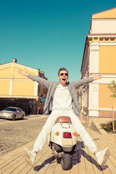Knappe vrolijke man zit op een scooter — Stockfoto