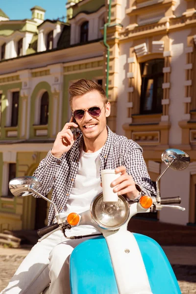 Jonge knappe man permanent in de buurt van de scooter houden een kopje van co — Stockfoto