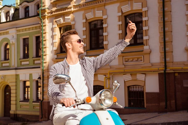 Glücklich schöner Mann sitzt auf dem Roller macht Selfie-Foto — Stockfoto