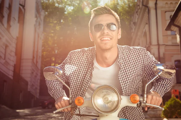 Jovem bonito alegre com óculos andando na moto — Fotografia de Stock