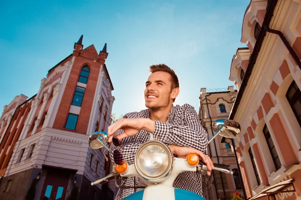 Vrolijke knappe jonge man met bril zittend op de motorbik — Stockfoto