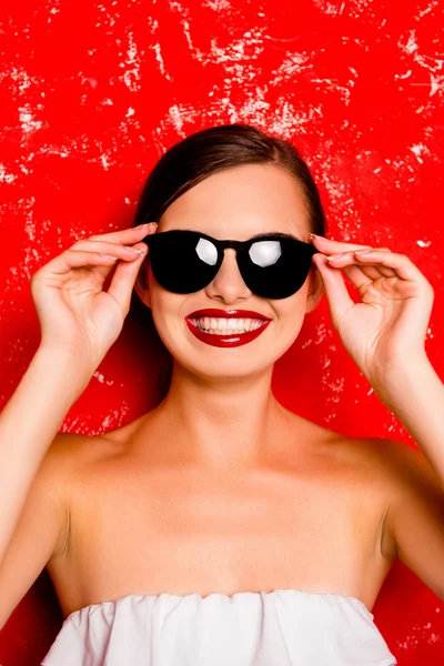 Feliz linda chica sosteniendo las gafas contra el fondo rojo — Foto de Stock
