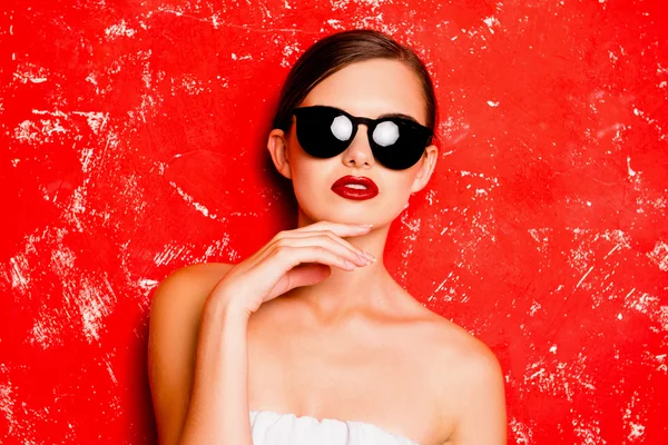 Chica glamurosa con gafas frescas posturando contra el rojo b — Foto de Stock