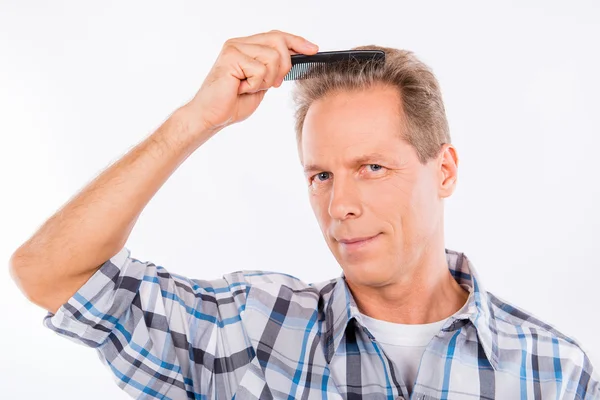 Handsome keen aged man combing his hair — Stock Photo, Image