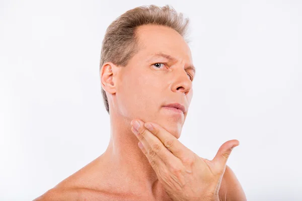 Handsome disturbed aged man touching his face after shave — Stock Photo, Image