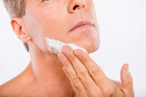 Closeup photo of a handsome man smearing shaving foam on his chi — Stock Photo, Image