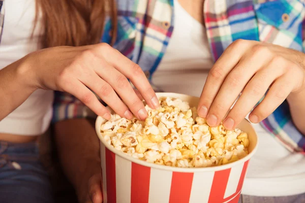 Jovem mulher e homem comendo pipocas no cinema — Fotografia de Stock