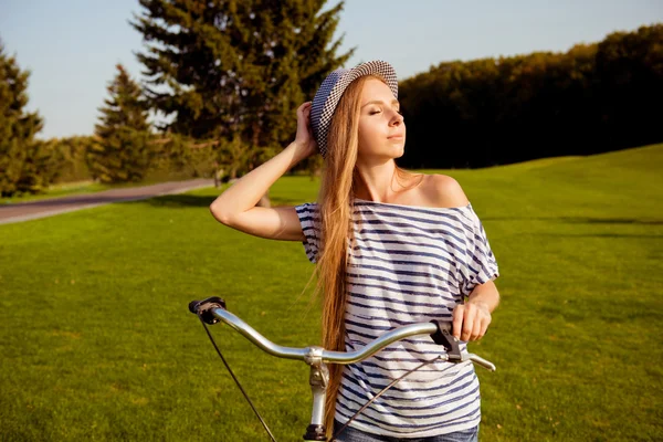 Bonita chica con un sombrero disfrutando del sol con una bicicleta —  Fotos de Stock