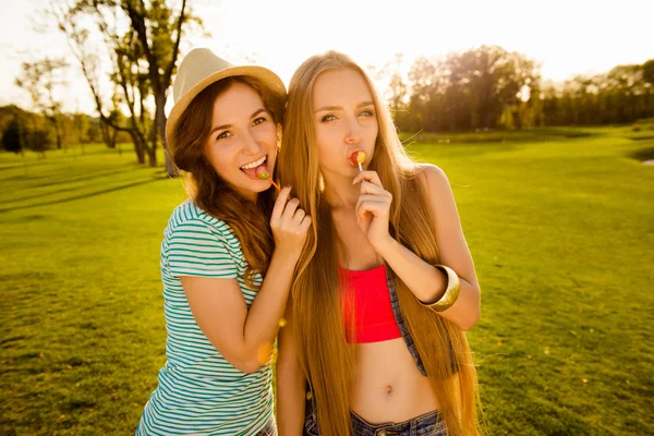 Two playful sexy girls licking lollipops — Stock Photo, Image