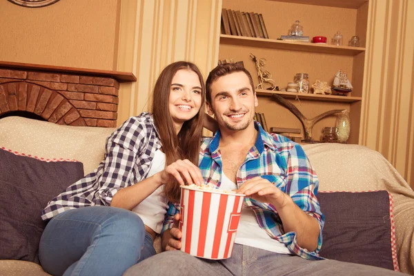 Lachen paar genieten van lettend op een film thuis op de Bank — Stockfoto