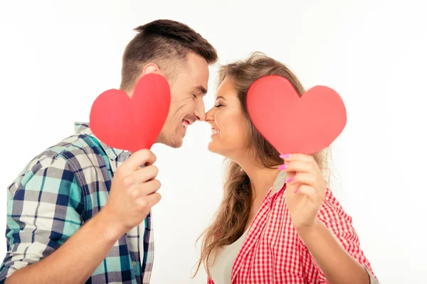 Pareja feliz enamorada sosteniendo dos corazones de papel besándose — Foto de Stock