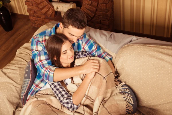 Χαριτωμένο ζευγάρι στον καναπέ κάτω από το καρό — Φωτογραφία Αρχείου