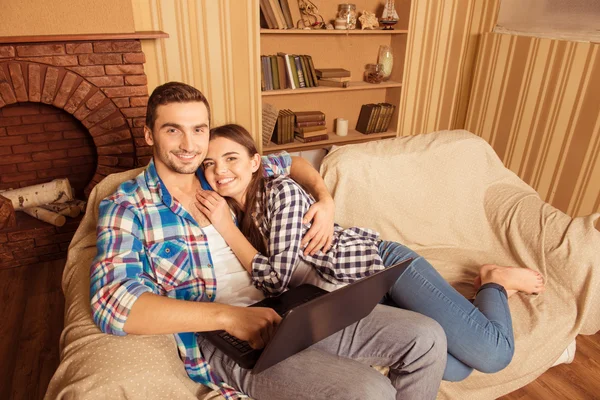 Happy couple in love with laptop sitting on the sofa — Stock Photo, Image