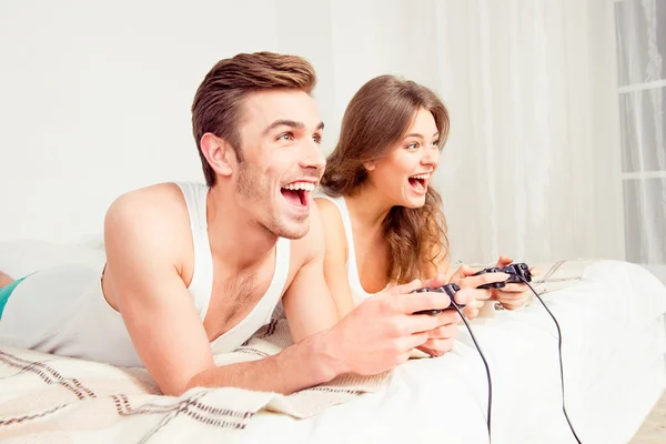Vrolijke paar in hou van het spelen van videospelletjes met joysticks op th — Stockfoto