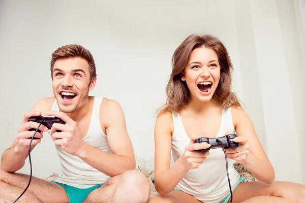 Jong paar in liefde thuis spelen spelletjes joysticks en laughin Rechtenvrije Stockafbeeldingen