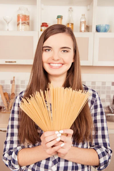 Aantrekkelijk meisje bedrijf pasta in de keuken — Stockfoto