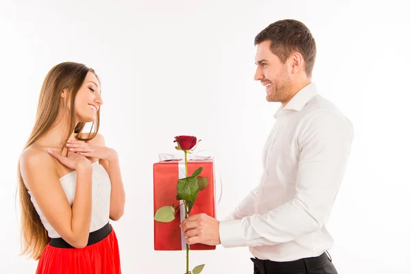 Sonriente chico dando a su novia un regalo y una rosa — Foto de Stock