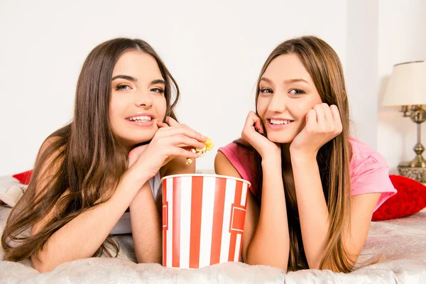Cheerful girls in pajamas sitting in plaid with popcorn — Stock Photo, Image