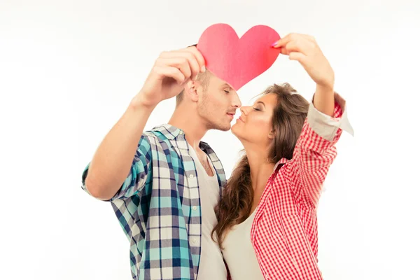 Vrolijke leuk paar verliefd holding papier hart en kussen — Stockfoto