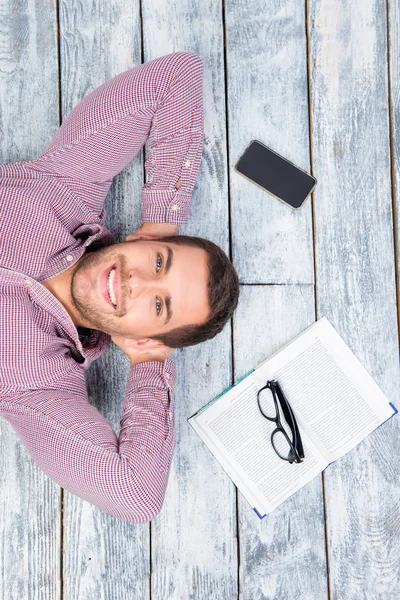 Vista superior de la foto de un hombre sonriente tirado en el suelo con — Foto de Stock